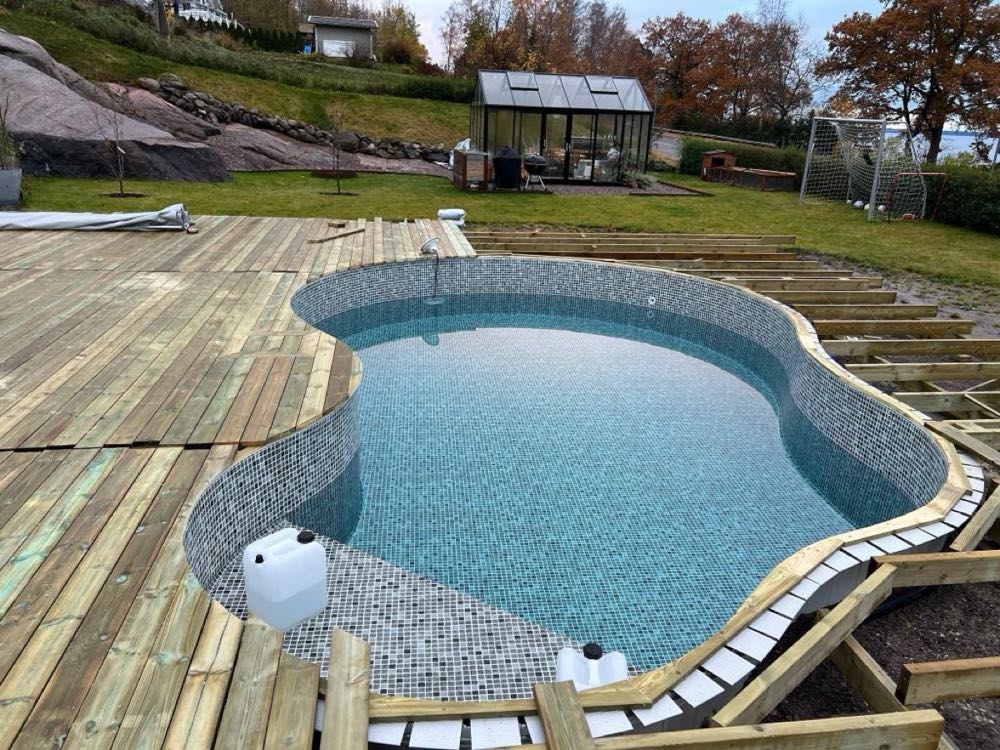 Pool med trädäck och stenlagd poolkant